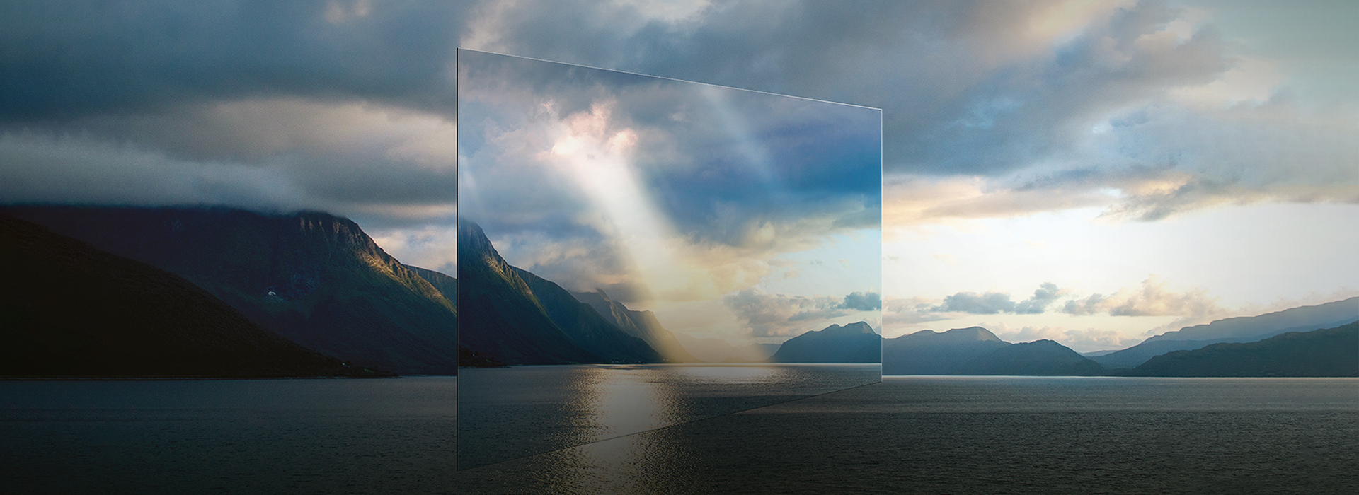 An OLED display floats in front of a lake and mountains with sunlight streaming through clouds, showing vivid, lifelike image quality.