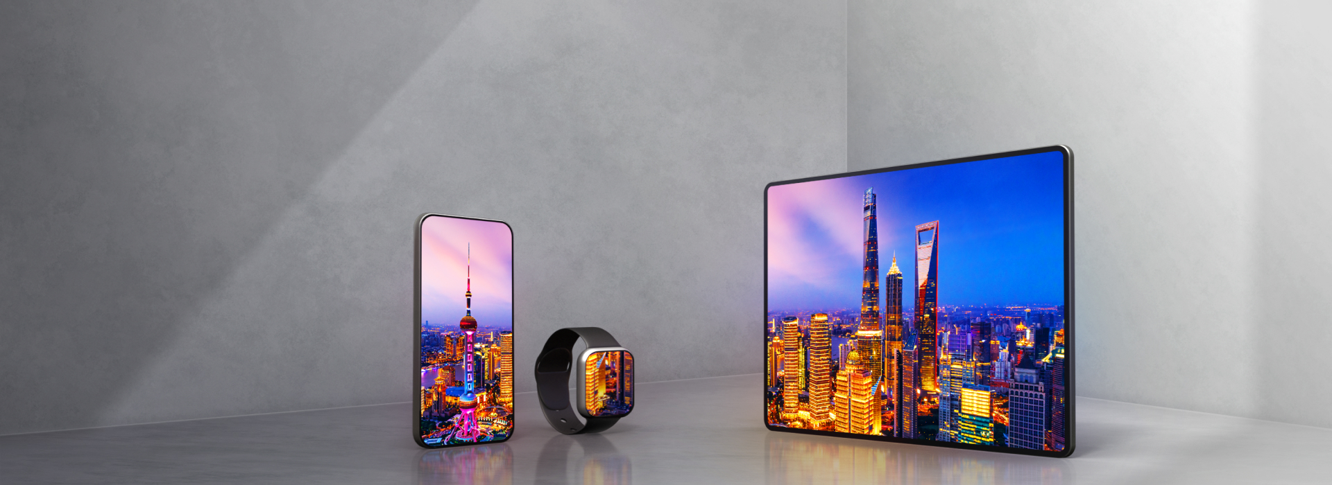 A smartphone, smartwatch, and tablet sit side-by-side on a gray background, all three displaying colorful nighttime photos on OLED displays.